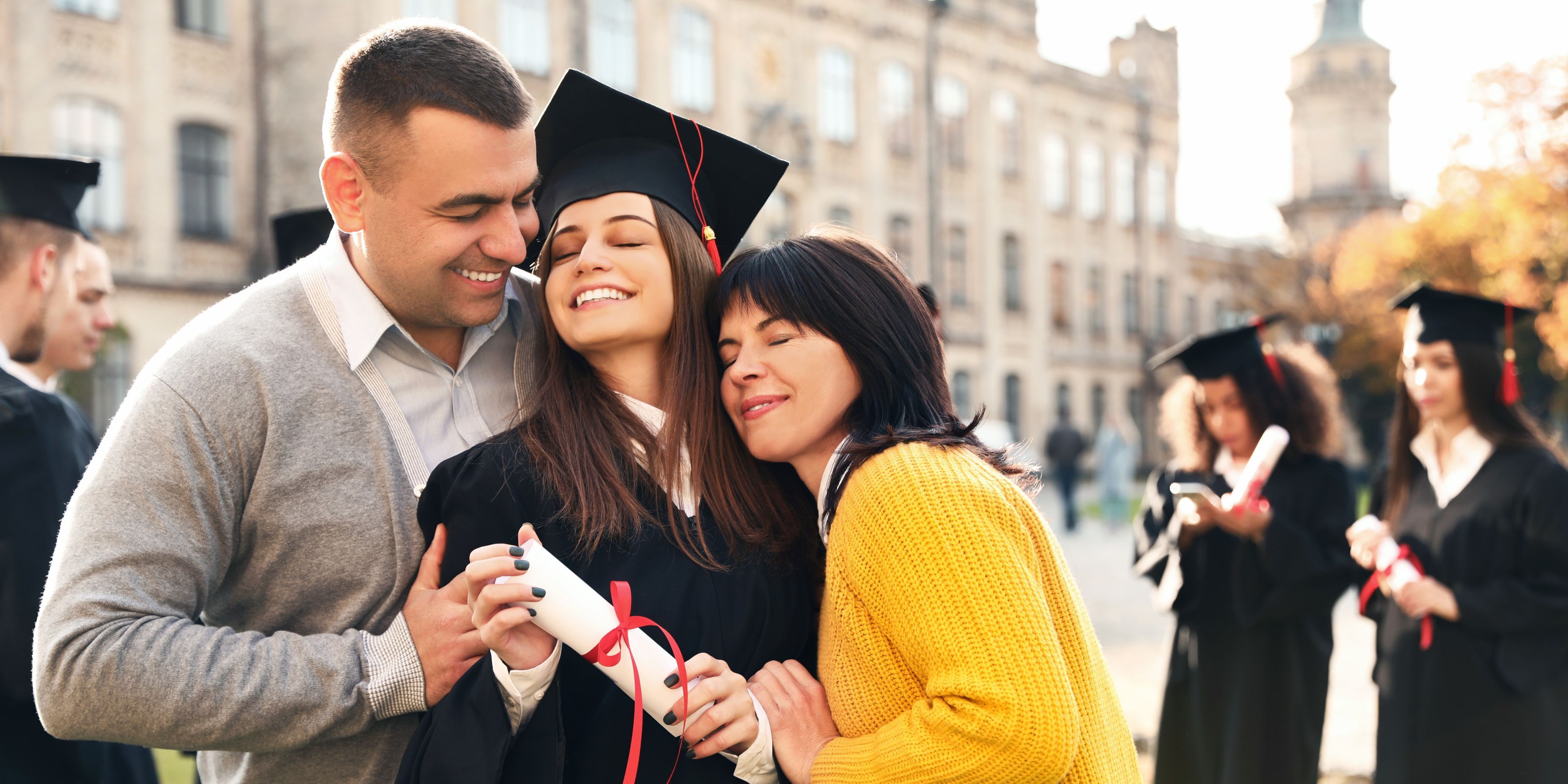 college parents hugging their graduate